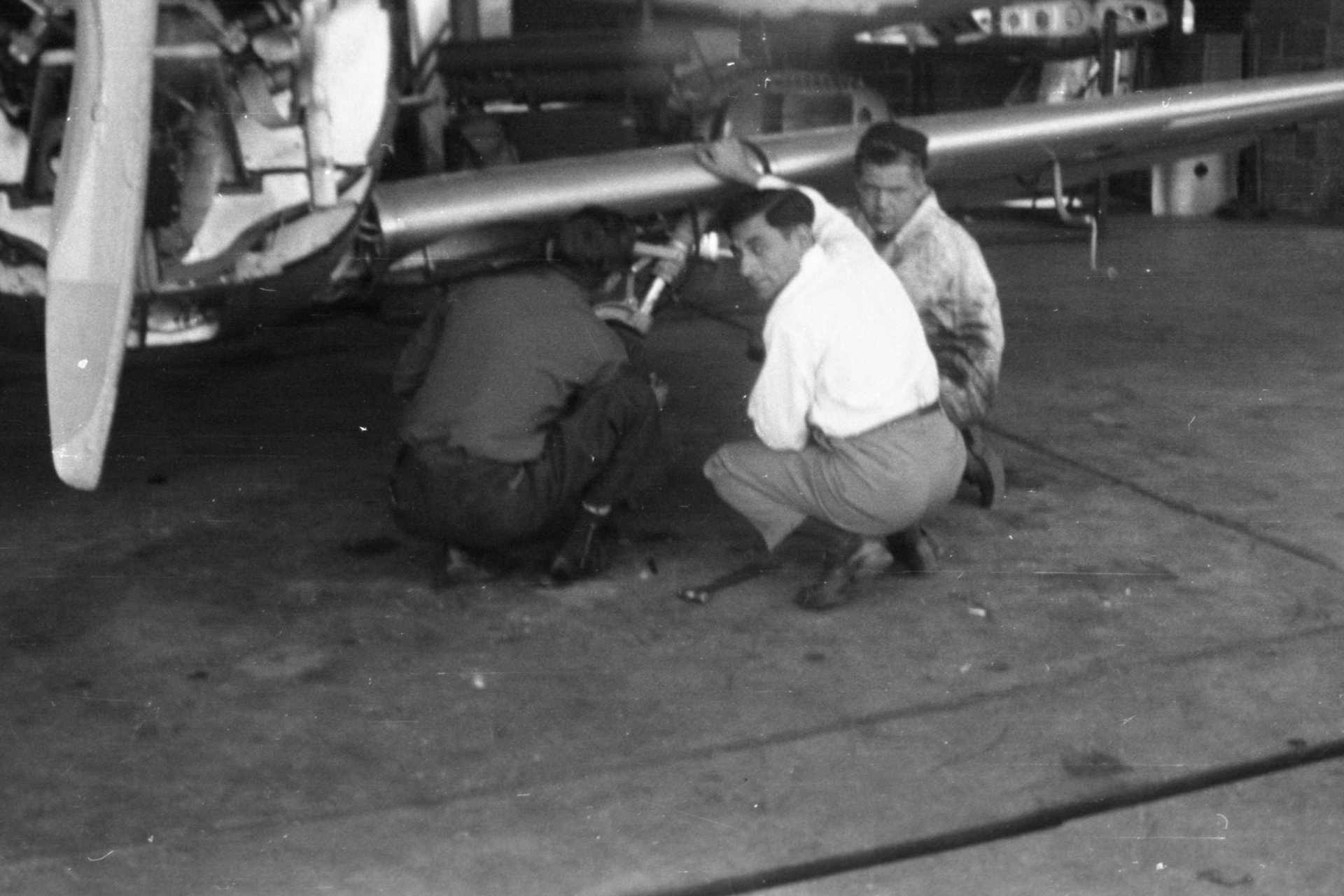 Tony Riccio and two unknown people inspecting a Globe Swift's left landing gear.
