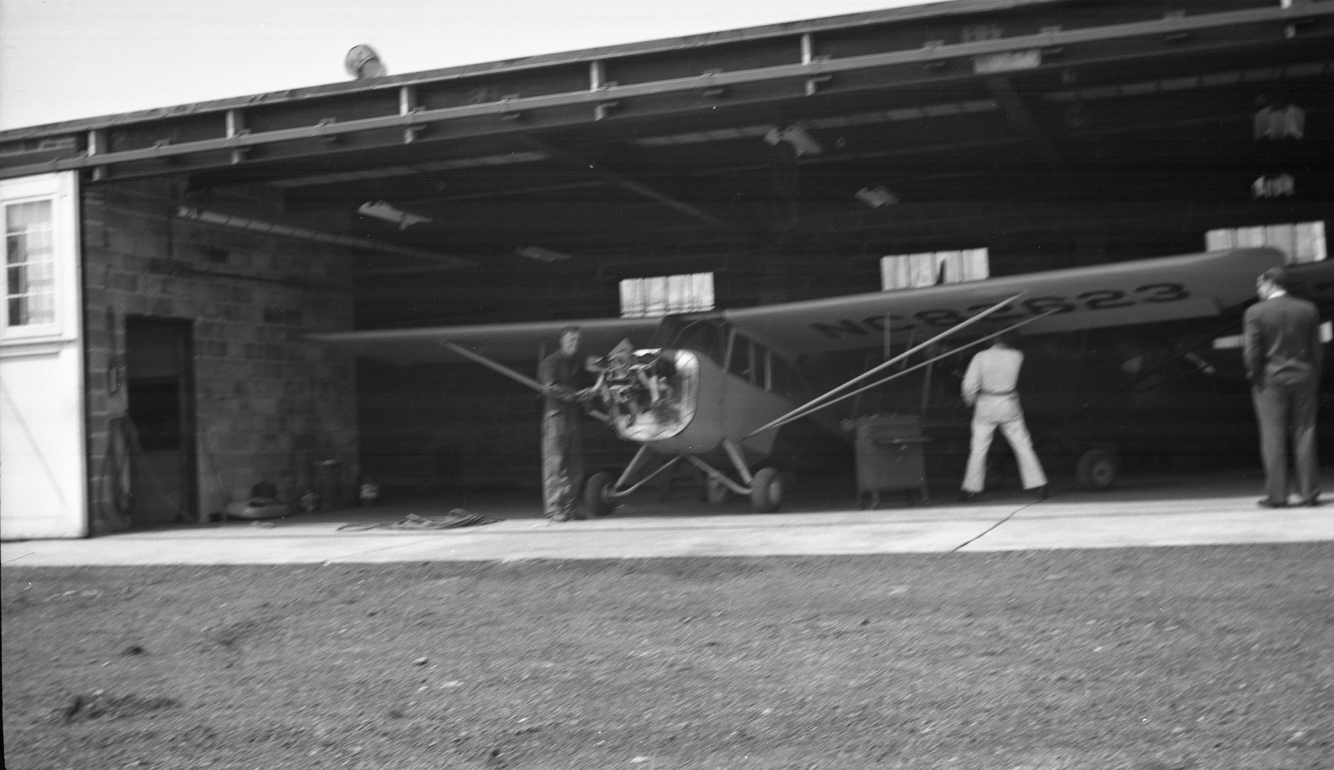 Three unknown people working on an airplane in the Maintenance shop at Buffalo Airpark.