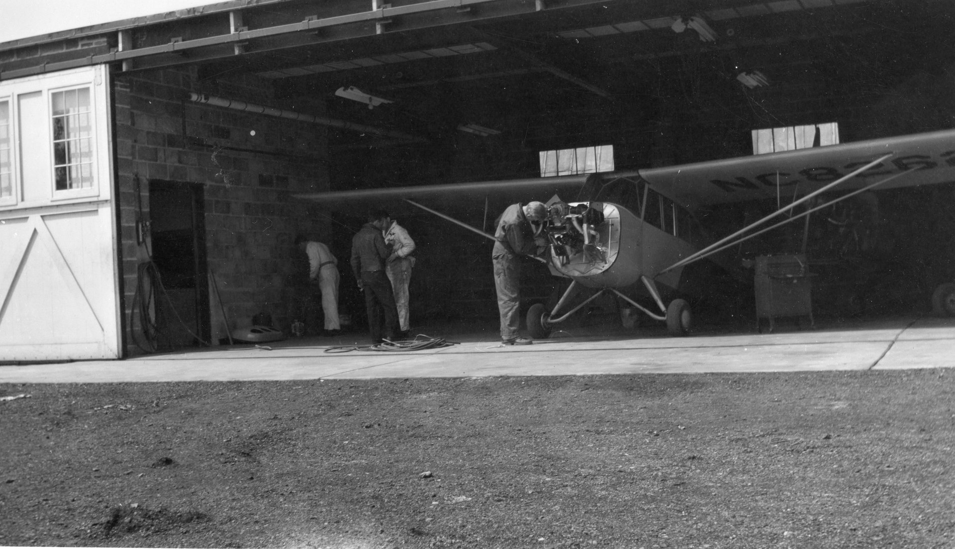 Four unknown people working on an airplane in the Maintenance shop at Buffalo Airpark.