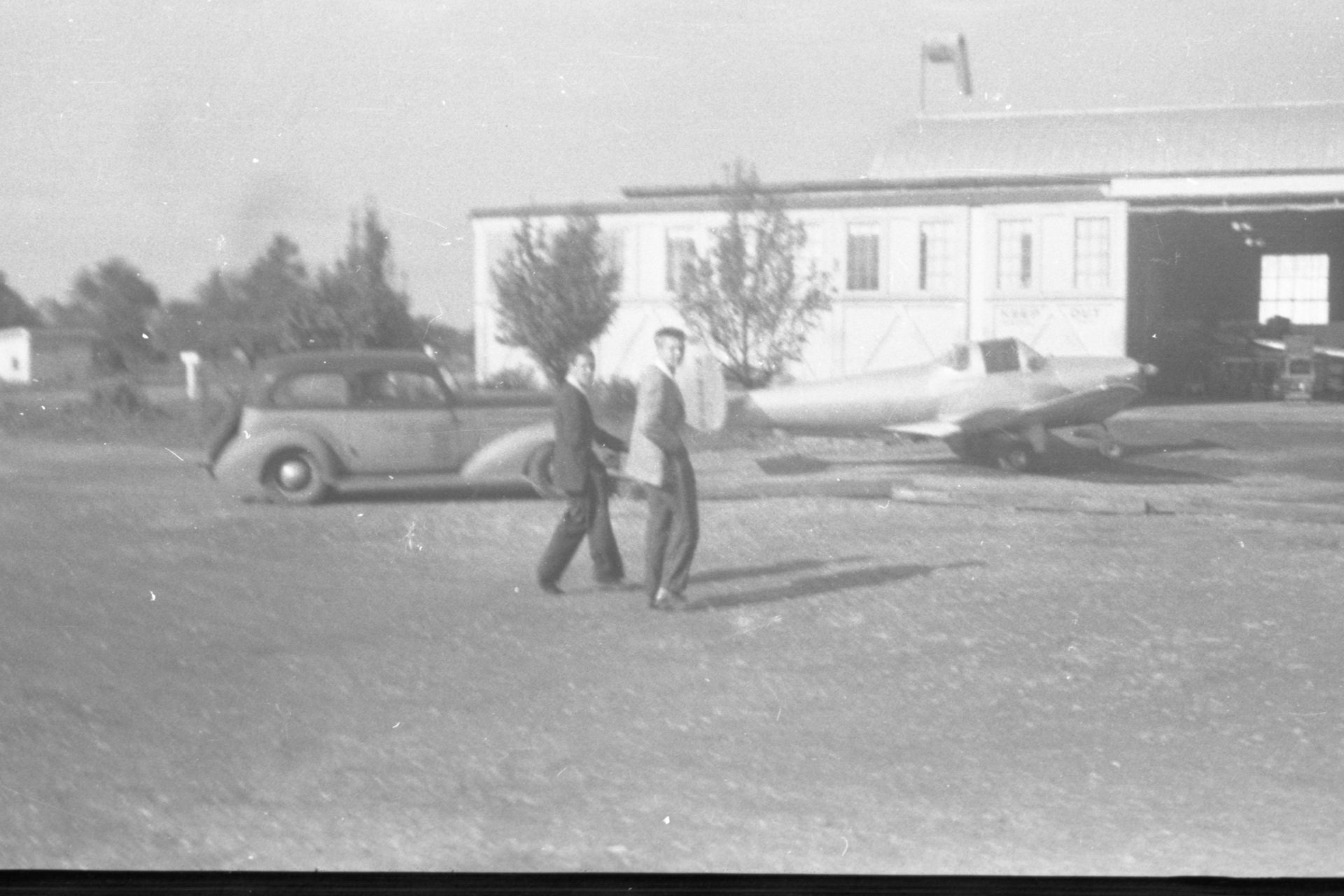 Two unknown people walking towards the Maintenance shop at Buffalo Airpark.