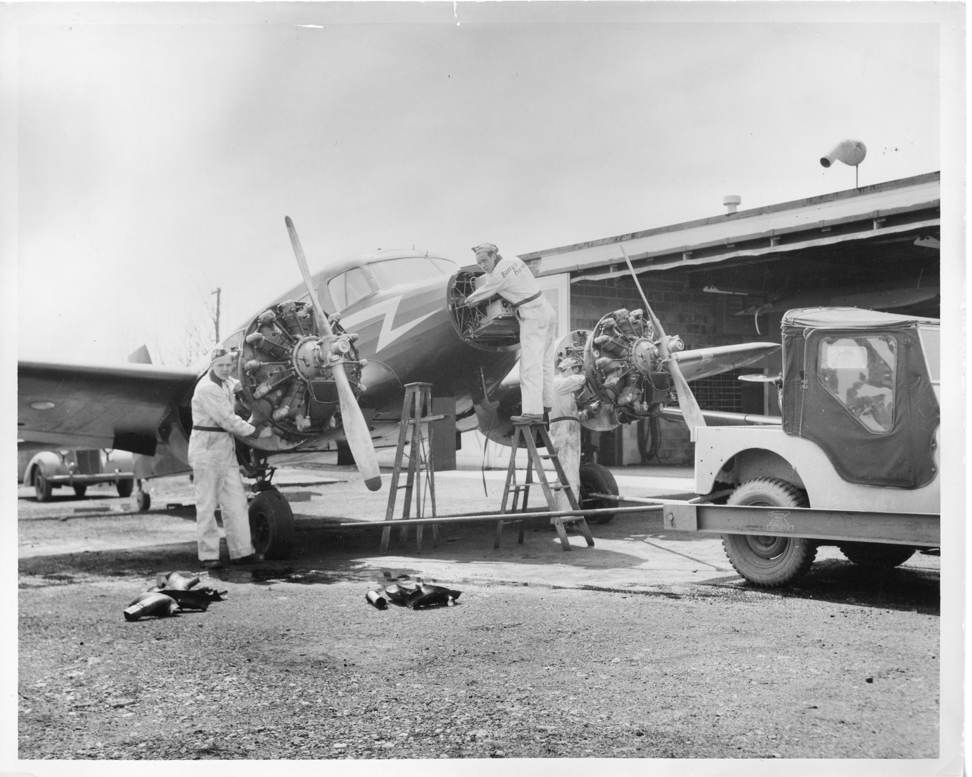 Three unknown mechanics are working on a Cessna T-50 outside of the Maintenance shop at Buffalo Airpark.