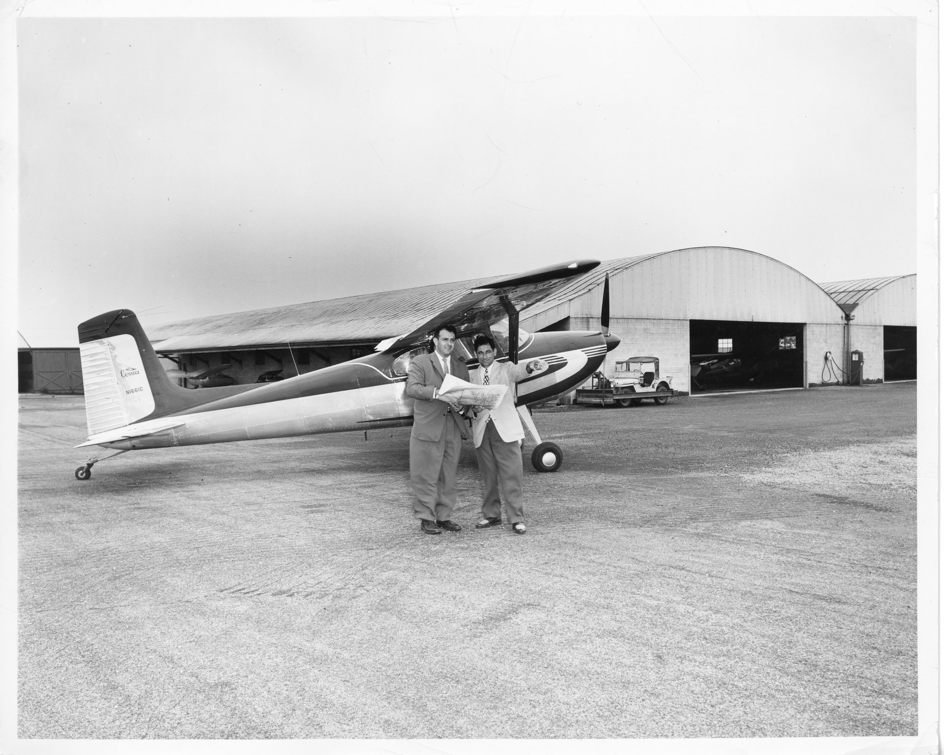 Tony Riccio giving directions to an unknown pilot with a Cessna 180 parked in front of the Twin hangars at Buffalo Airpark.