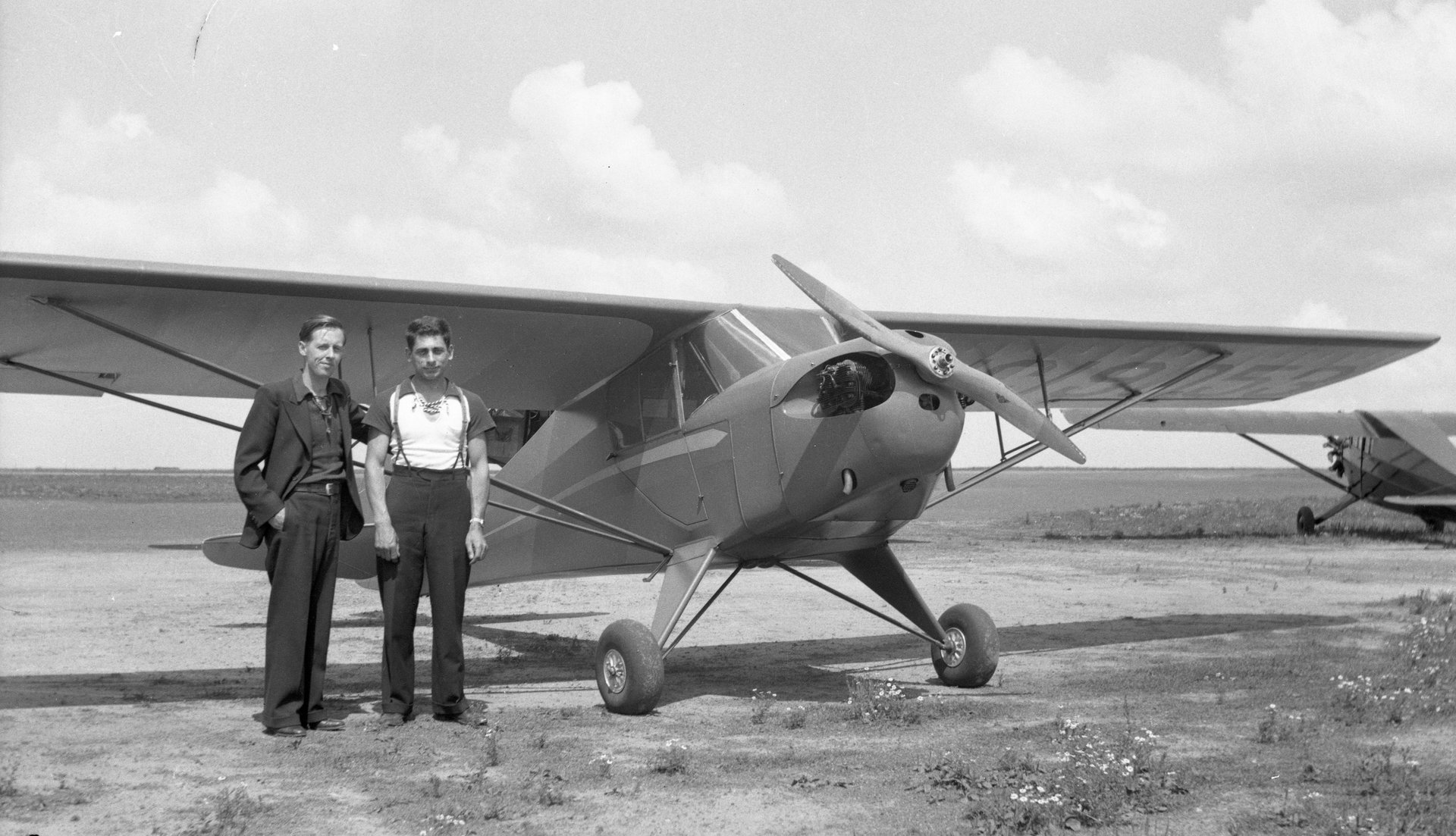 Tony Riccio and an unknown person standing next to a Taylor "Cub" E-2 airplane.