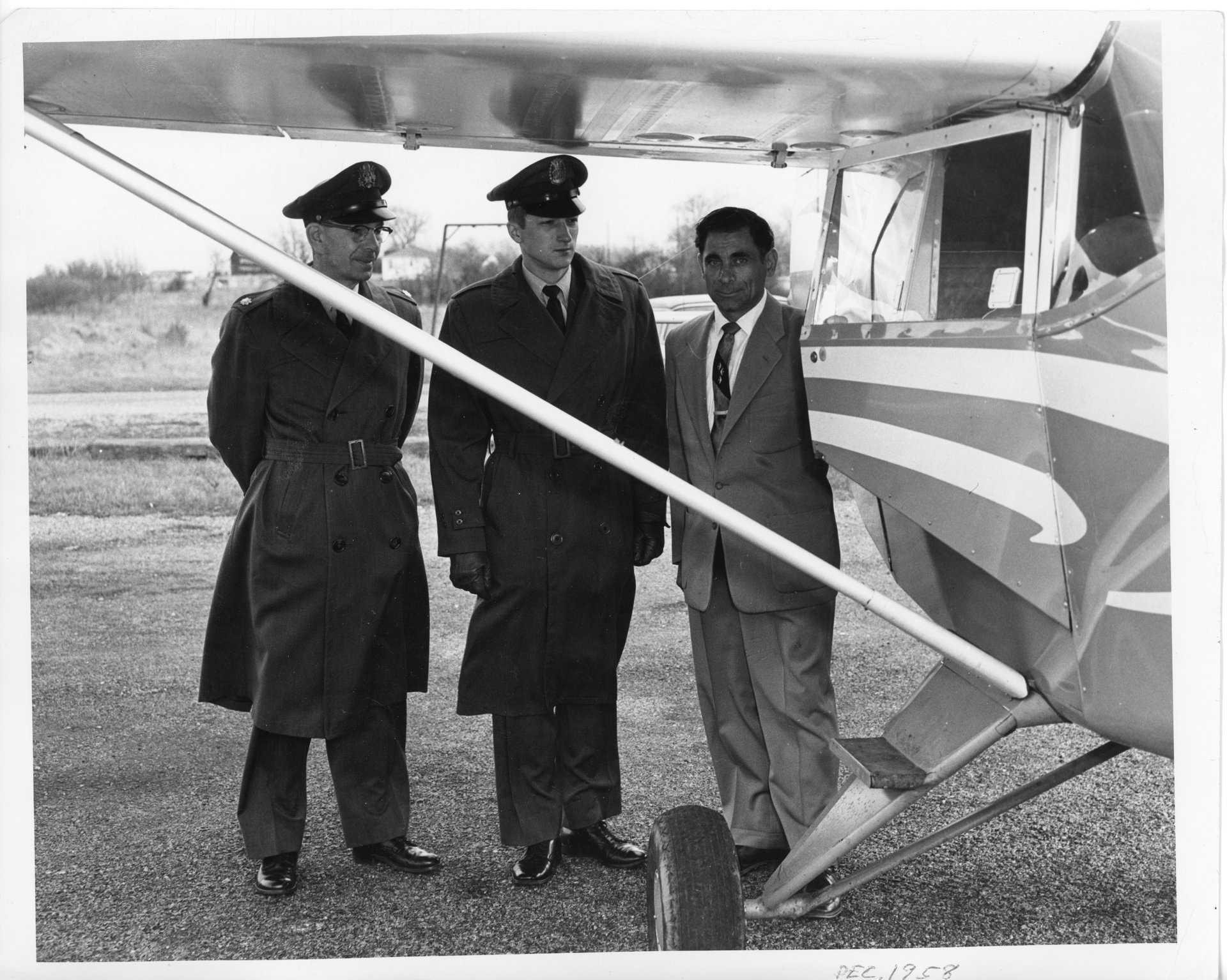 Tony Riccio and two unknown people standing next to an airplane at Buffalo Airpark in December 1958.