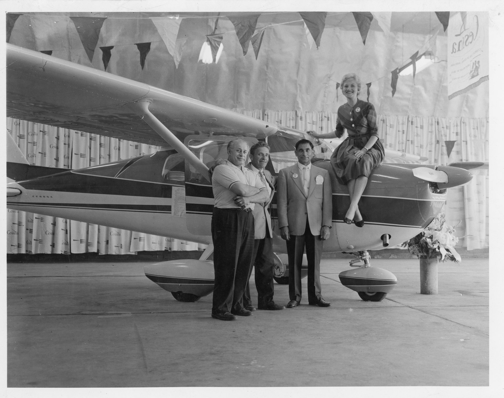 Tony Riccio and three unknown people standing next to a Cessna airplane inside the Buffalo Airpark's Quonset hangar during a Cessna marketing event.