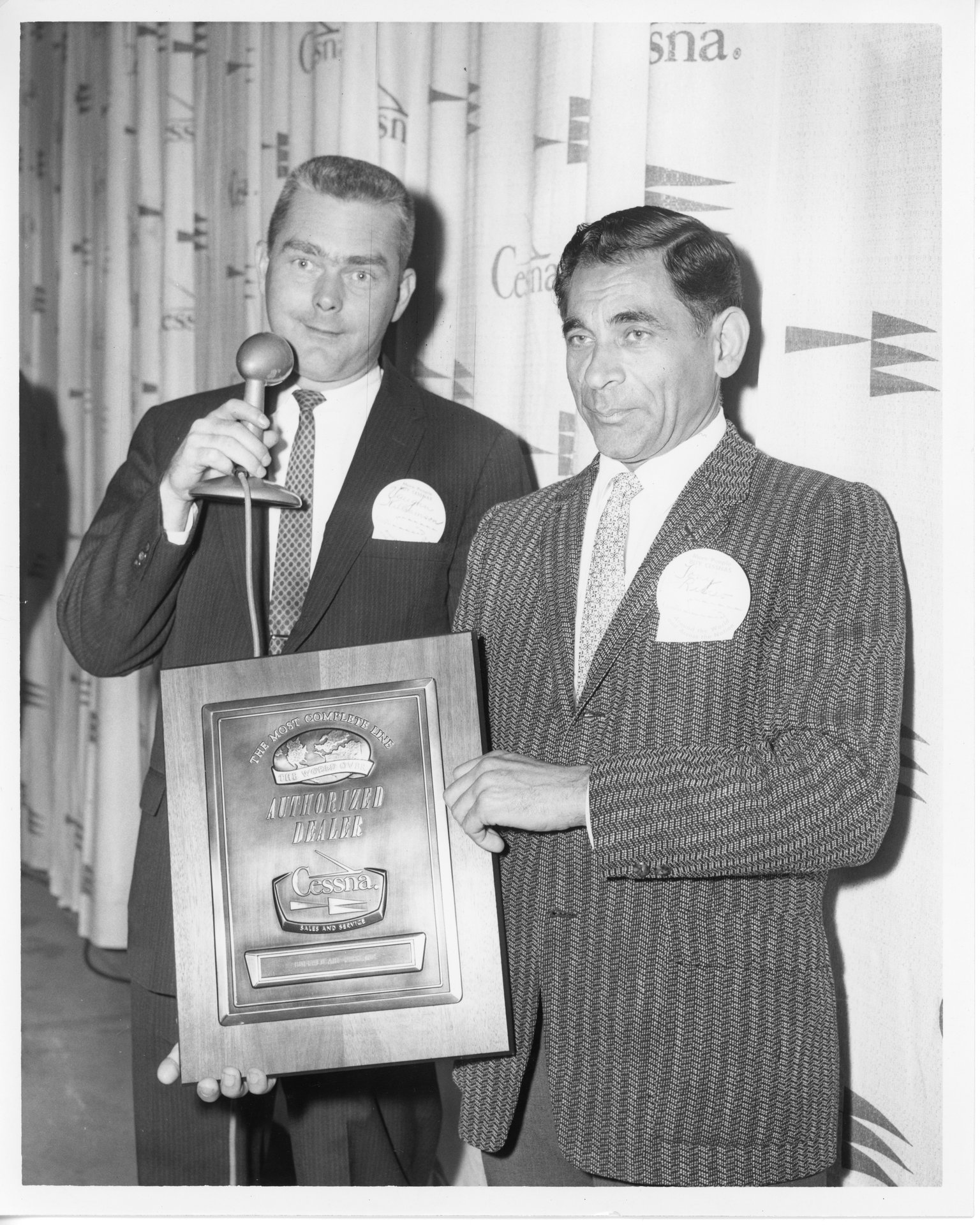 Tony Riccio holding his Authorized Dealer plaque from Cessna standing next to an unknown person.